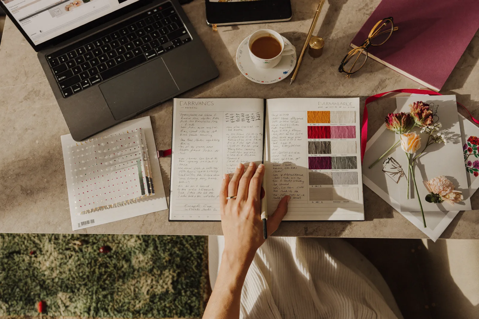 Wedding planner's desk with notebook, swatches, and florals