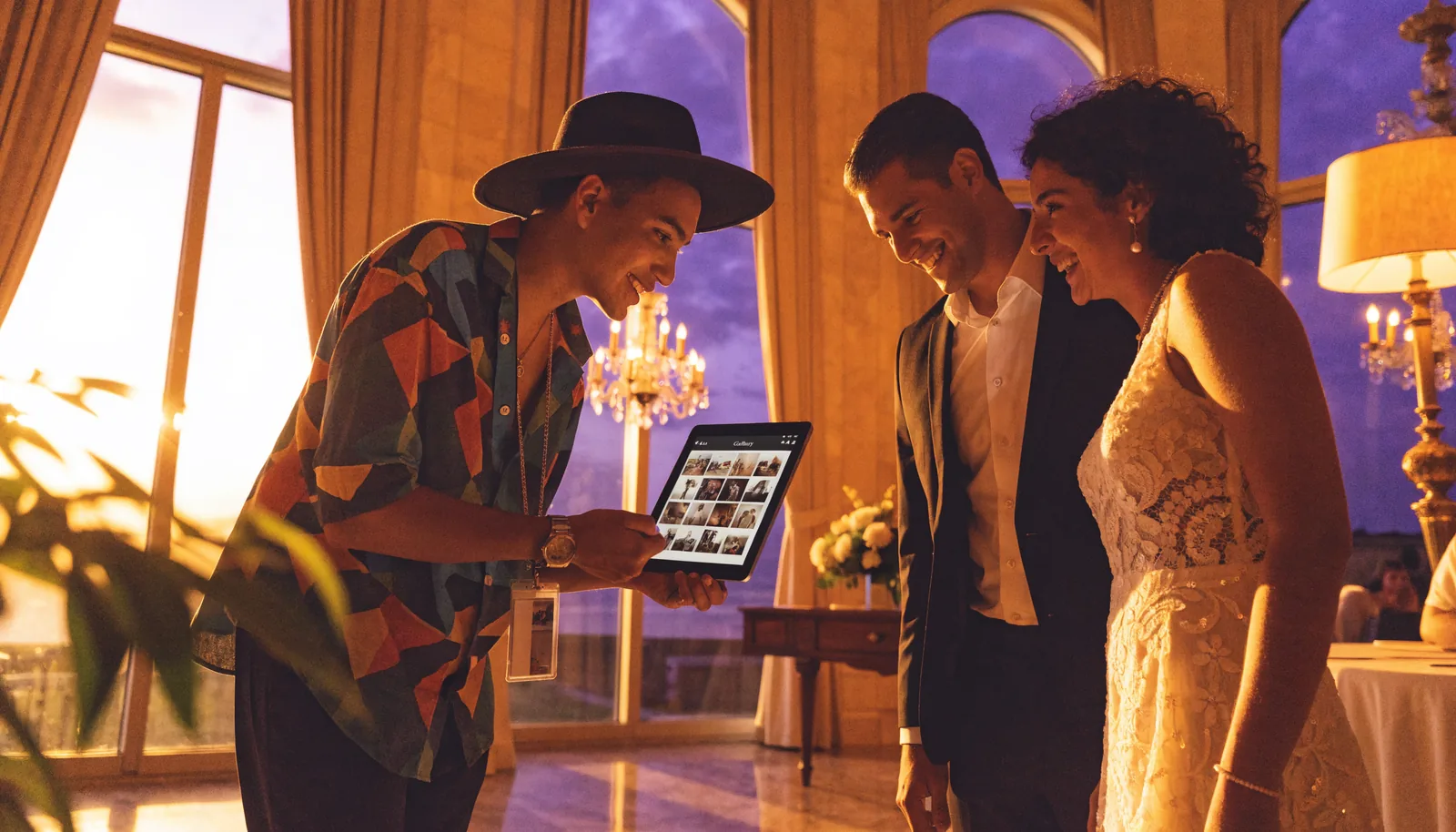 Wedding photographer showing gallery previews on a tablet to a smiling couple