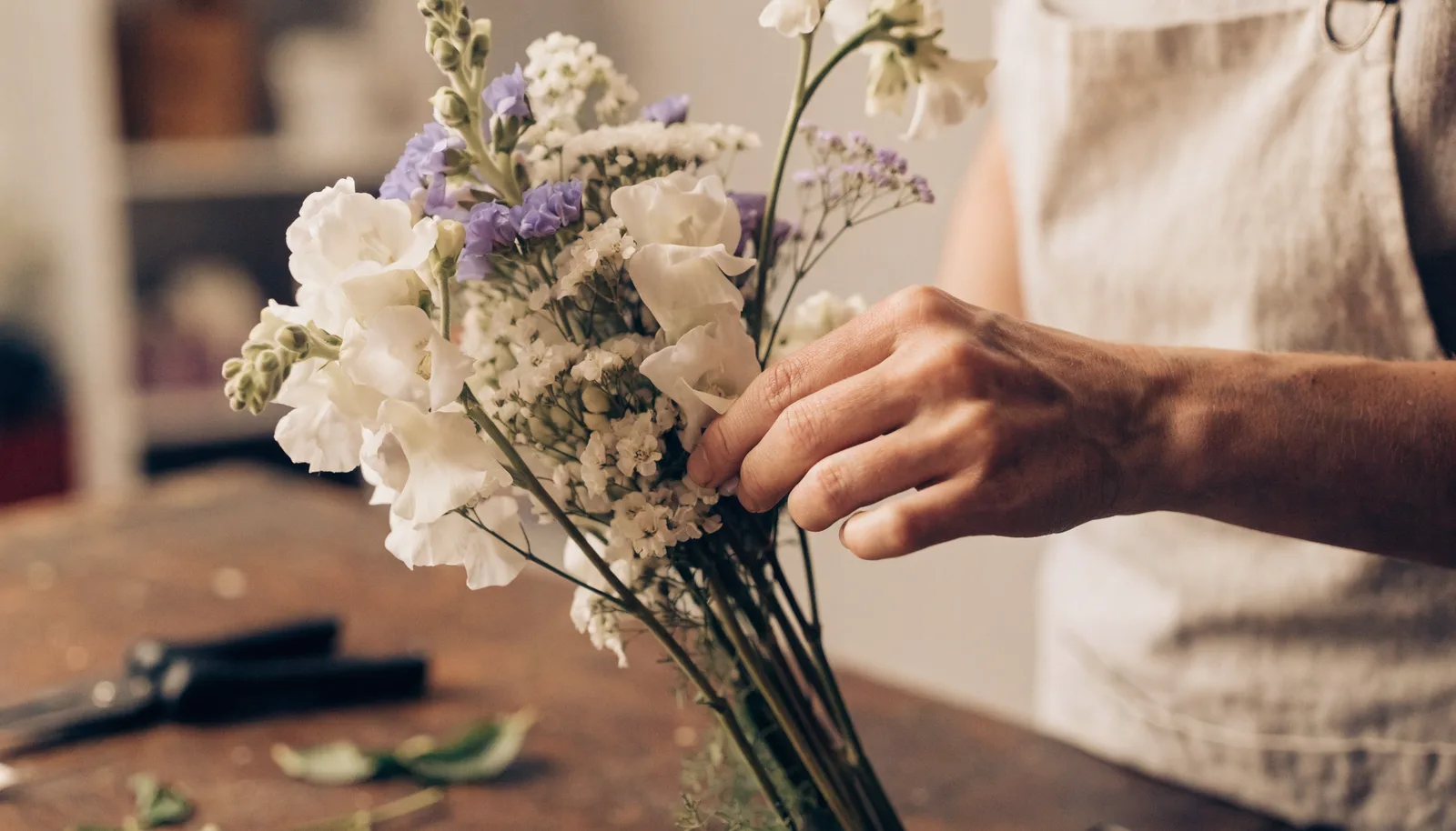 A floral designer arranging seasonal flowers in a warm, naturally lit studio